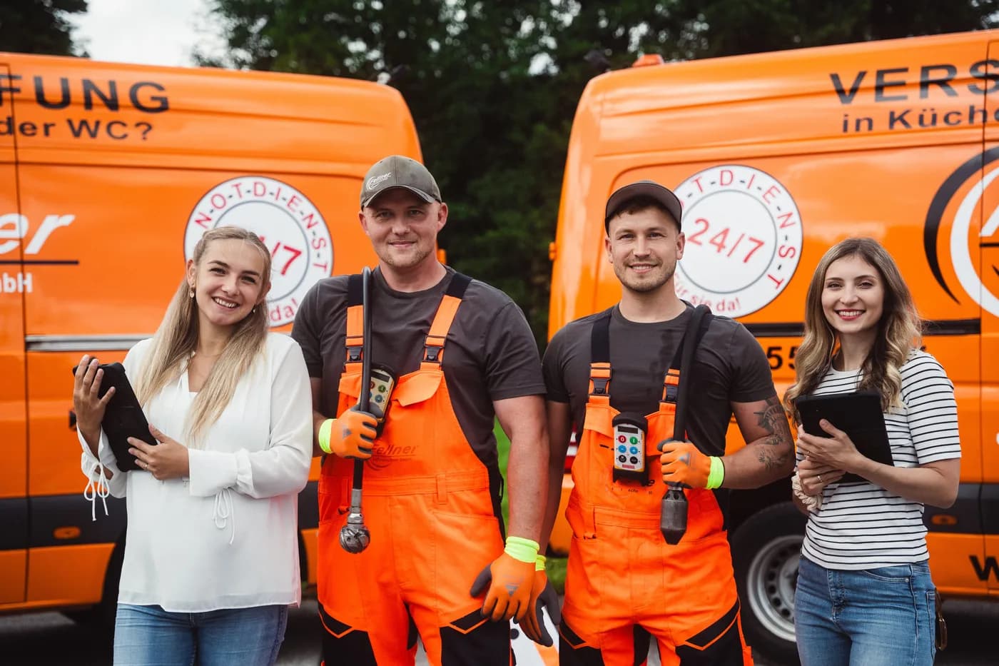 Team der Fellner Abflusstechnik GmbH vor den orangen Einsatzfahrzeugen in Neukirchen an der Vöckla