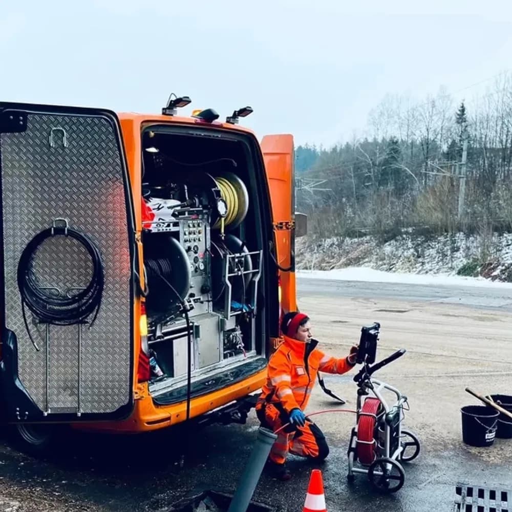 Team der Fellner Abflusstechnik GmbH vor den orangen Einsatzfahrzeugen